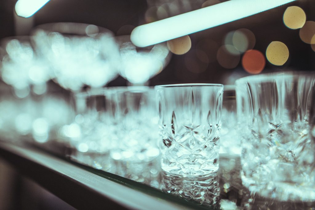 © Sergiu Andrés Close-up of a crystal glass on a bar counter with blurred city lights in the background.